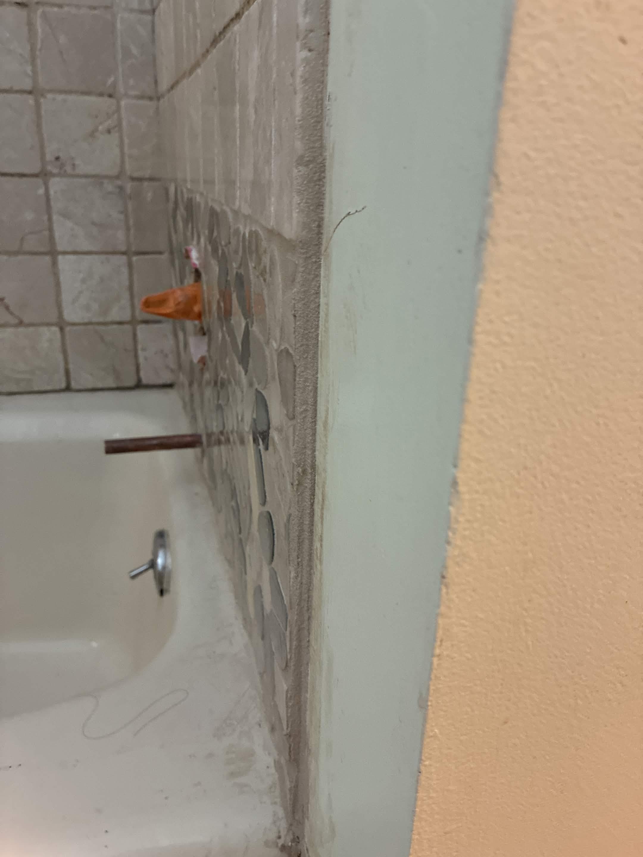 Detail of freshly caulked corner joint between tub surround and adjacent wall