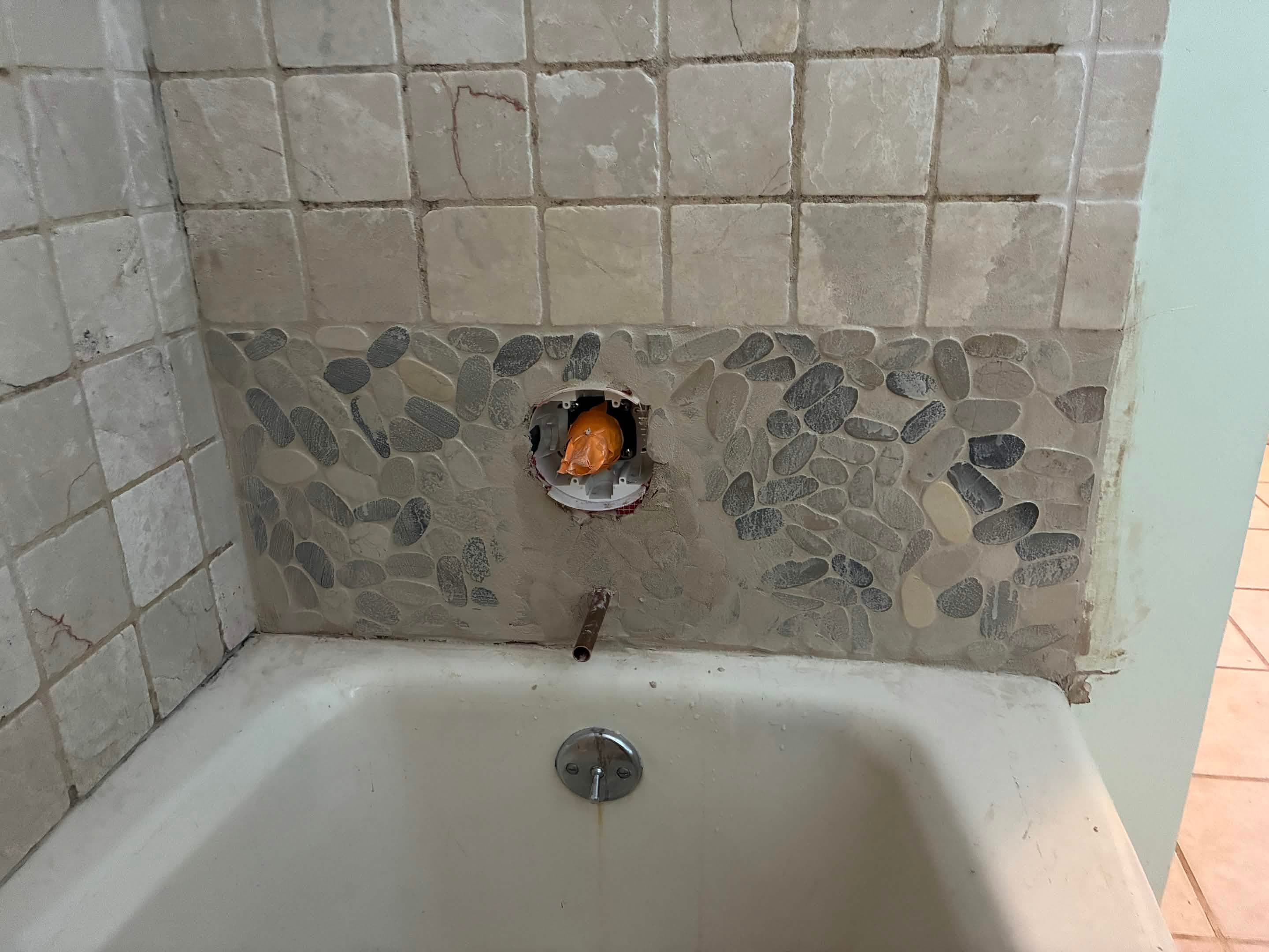 Pebble mosaic band after grout applied on tub surround
