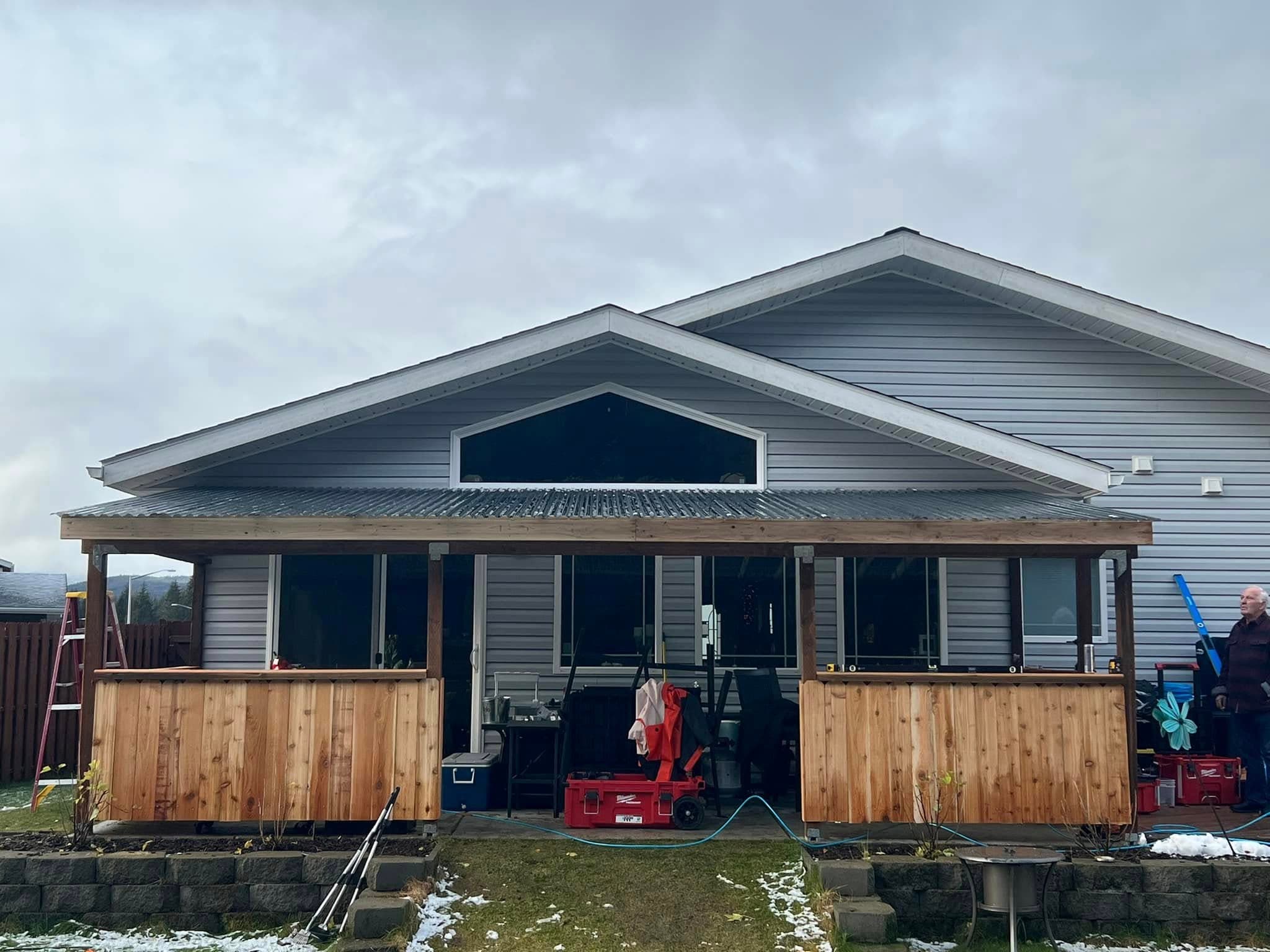 Covered porch addition with cedar railing on Juneau residence by Sourdough Construction